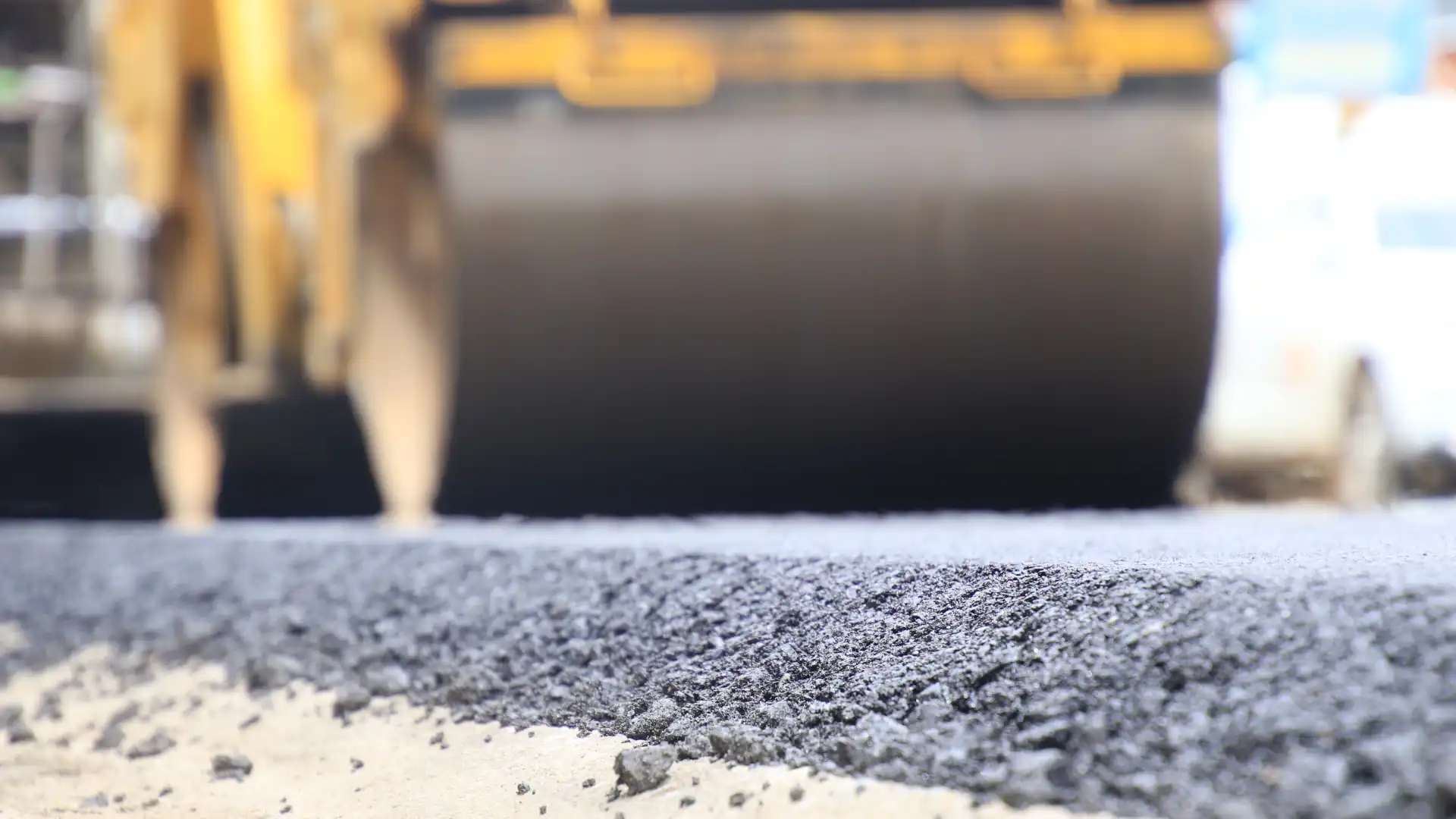 Asphalt patching as steamroller moves over fresh asphalt mix