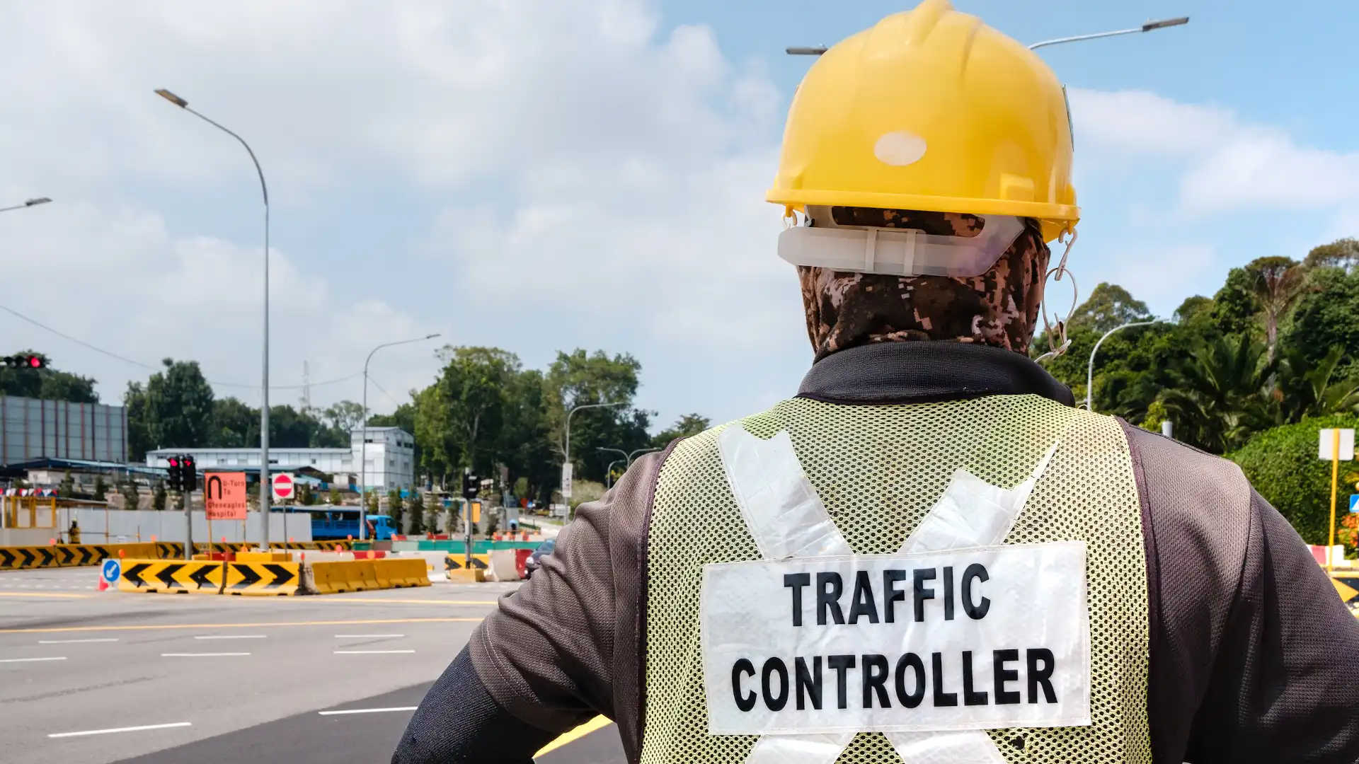 Traffic controller worker stands at the roadside managing traffic effectively with traffic control training.